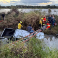 Carro capota e fica parcialmente submerso em sanga na BR-101