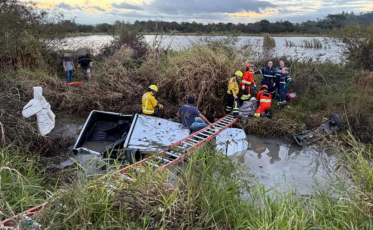 Carro capota e fica parcialmente submerso em sanga na BR-101