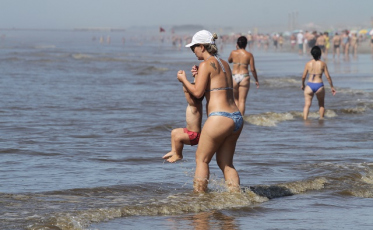 Guarda-sóis na areia, veranistas ao mar